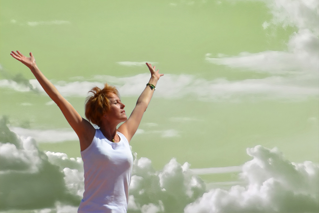 Cécilie Briens, thérapeute en gestion du stress et professeure de Hatha Yoga, bras levés vers le ciel sur fond vert apaisant, symbolisant l’équilibre et le bien-être.